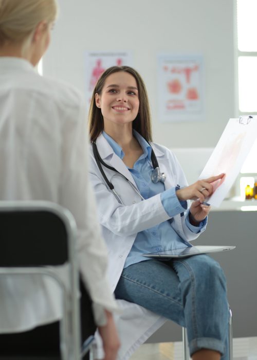 Doctor and patient discussing something while sitting at the table . Medicine and health care concept.