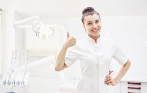 happy-young-female-dentist-with-tools-over-medical-Z3WGLGH-1.jpg